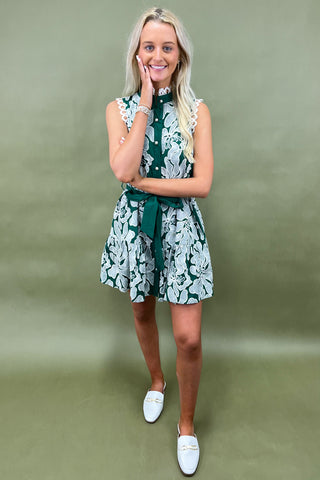 Woman wearing a green and white floral dress against a green background