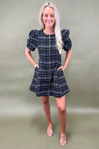 Woman wearing a black plaid dress against a green background