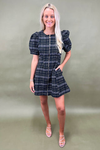Woman wearing a plaid dress against a plain background