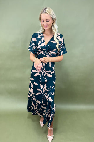 Woman wearing a dark blue dress with floral pattern on a green background