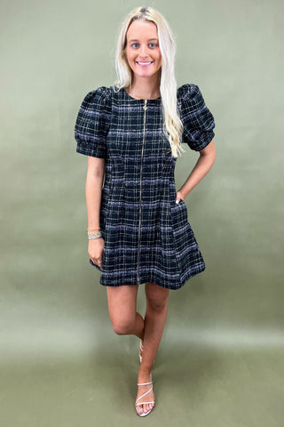 Woman wearing a plaid dress against a green background