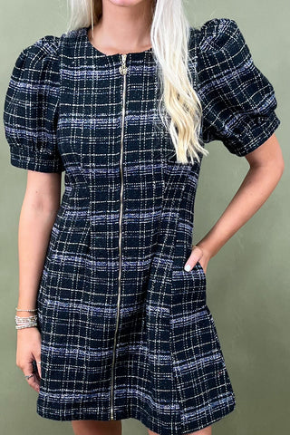 Woman wearing a navy and white checkered dress against a green background