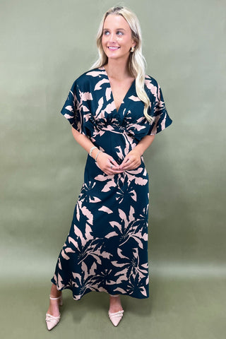 Woman wearing a navy floral dress against a green background