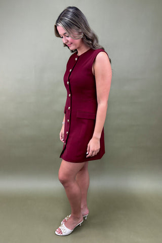 Woman wearing a red dress with white buttons against a green background