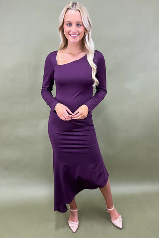 Woman wearing a purple dress against a plain background