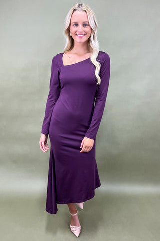 Woman wearing a purple dress against a plain background