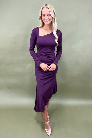 Woman wearing a purple dress against a plain background