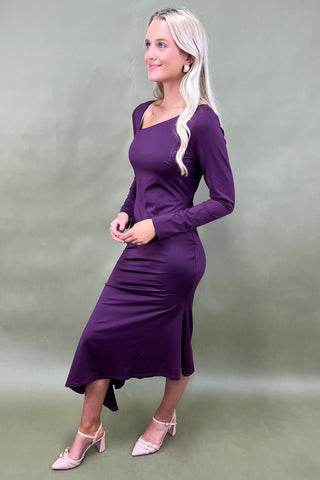 Woman wearing a purple dress against a plain background