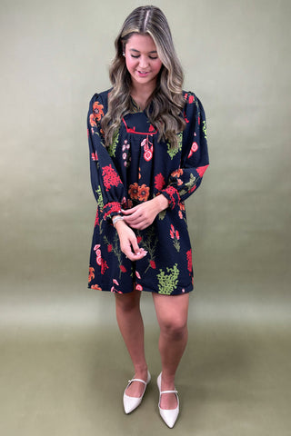 Woman wearing a navy floral dress against a plain background