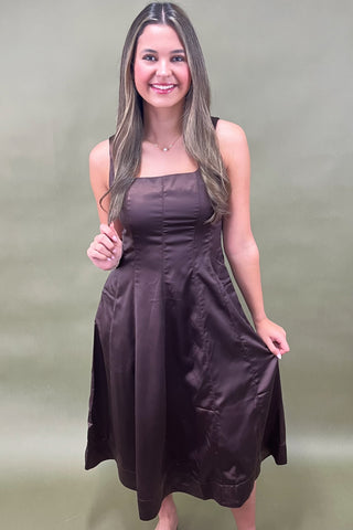 Woman wearing a brown dress against a green background