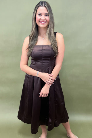 Woman wearing a brown dress against a green background