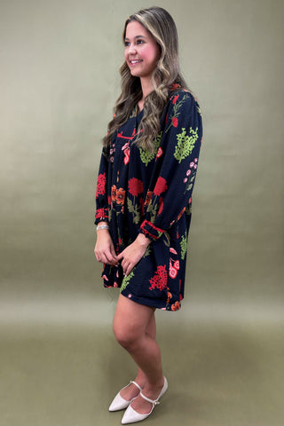 Woman wearing a dark floral dress against a plain background
