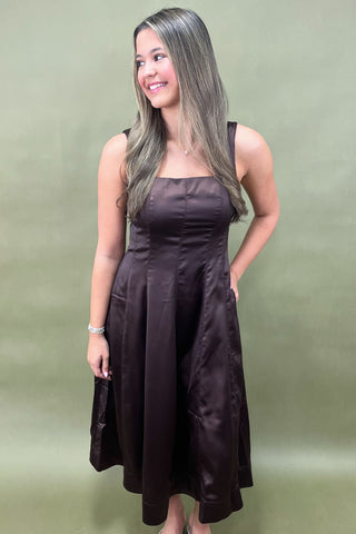 Woman wearing a brown dress against a green background