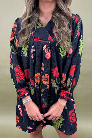 Navy dress with colorful floral pattern worn by a person on a green background