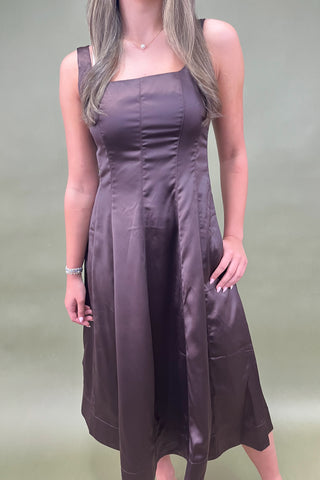 Woman wearing a brown dress against a green background