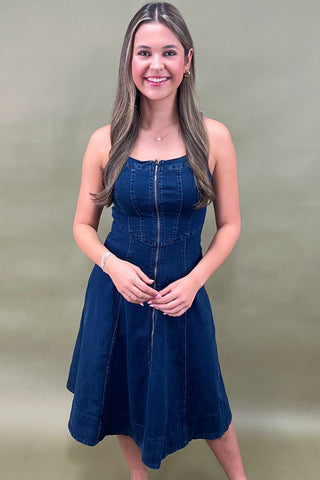 Woman wearing a blue denim dress against a plain background