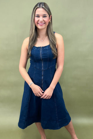 Woman wearing a blue denim dress against a plain background