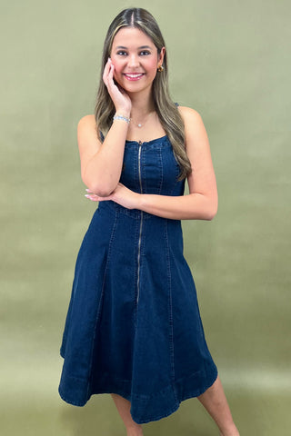 Woman wearing a blue denim dress against a plain background