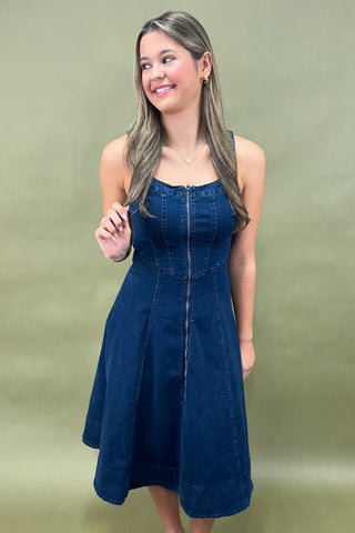 Woman wearing a blue denim dress against a plain background