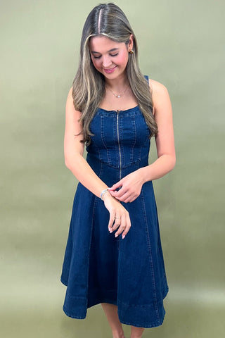 Woman wearing a blue denim dress against a plain background