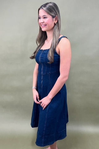 Woman wearing a blue denim dress against a plain background