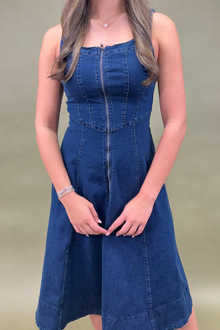 Woman wearing a blue denim dress against a plain background