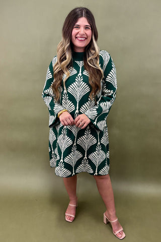 Woman wearing a green and white patterned dress against a solid background
