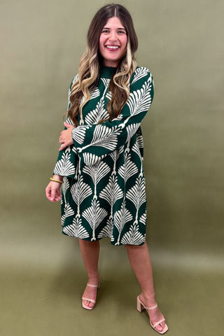 Woman wearing a green and white patterned dress against an olive green background