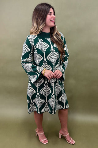 Woman wearing a green and white patterned dress against a plain background
