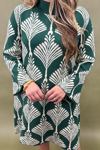 Green dress with white leaf pattern worn by a person against a plain background