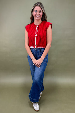 Woman wearing a red top and blue jeans against a green background