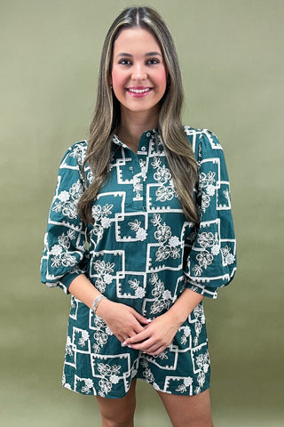 Woman wearing a green dress with white floral pattern against a green background