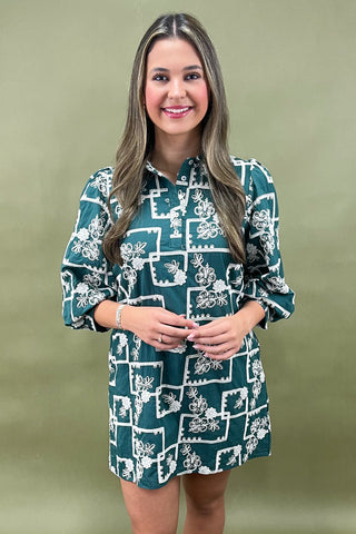 Woman wearing a green dress with white floral pattern against a green background