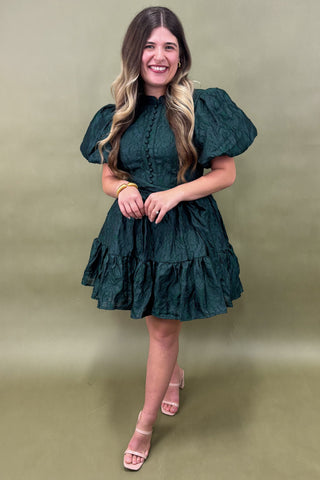 Woman wearing a green dress against a beige background