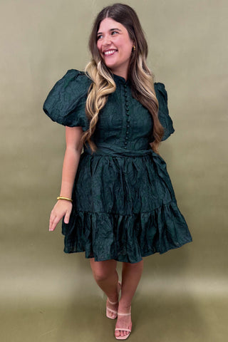 Woman wearing a green dress against a beige background