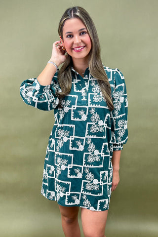 Woman wearing a green dress with white floral pattern against a green background