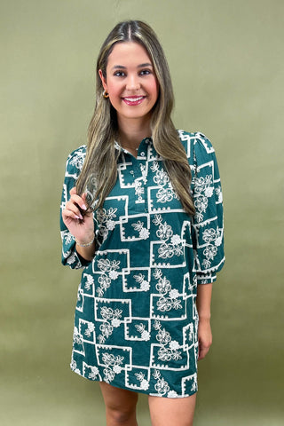 Woman wearing a green dress with white floral pattern against a green background