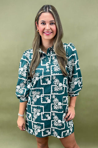Woman wearing a green dress with white floral pattern against a green background