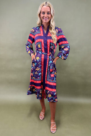 Woman wearing a colorful patterned dress against a plain background