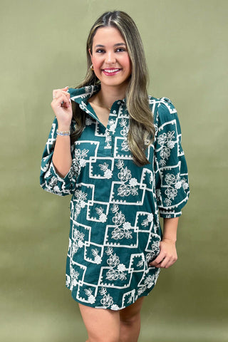 Woman wearing a green dress with white floral pattern against a green background
