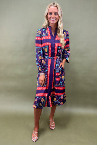 Woman wearing a colorful patterned dress against a plain background