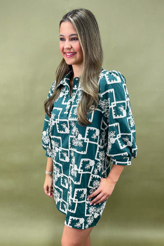 Woman wearing a green dress with white floral pattern against a green background