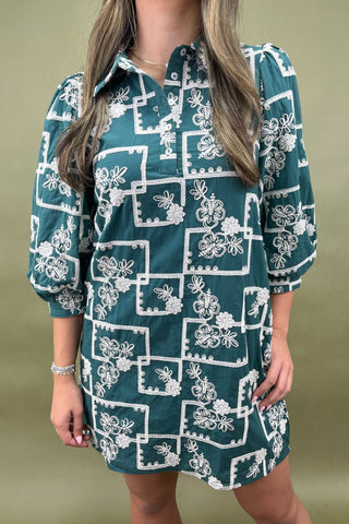 Woman wearing a green dress with white floral pattern against a green background