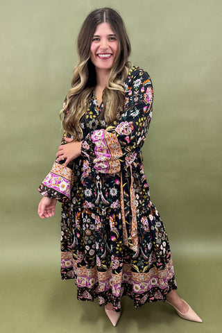 Woman wearing a long, floral-patterned dress on a green background