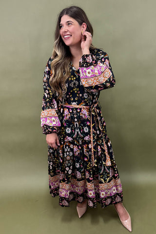 Woman wearing a long, patterned dress against a green background