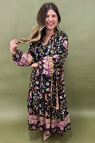 Woman wearing a long floral dress against a green background