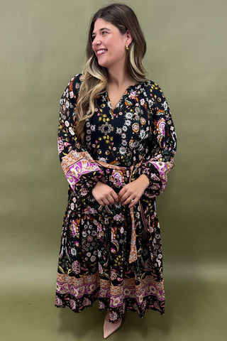 Woman wearing a floral dress with bell sleeves against a green background