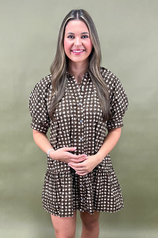 Woman wearing a brown and white patterned dress against a green background