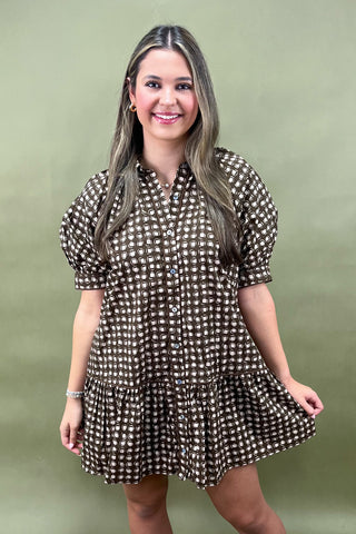 Woman wearing a brown checkered dress against a green background