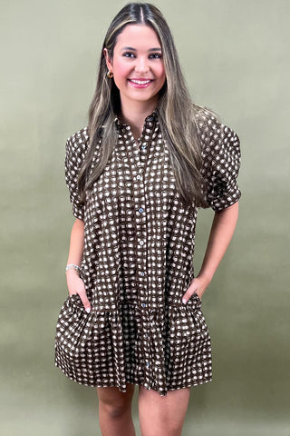 Woman wearing a brown checkered dress against a green background